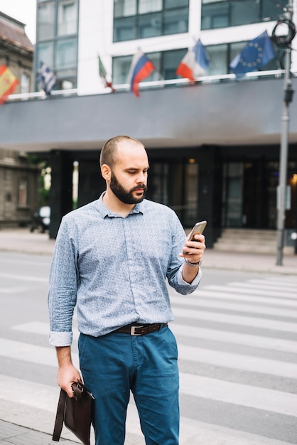 Bezpłatne zdjęcie poważny człowiek z telefonu na zewnątrz