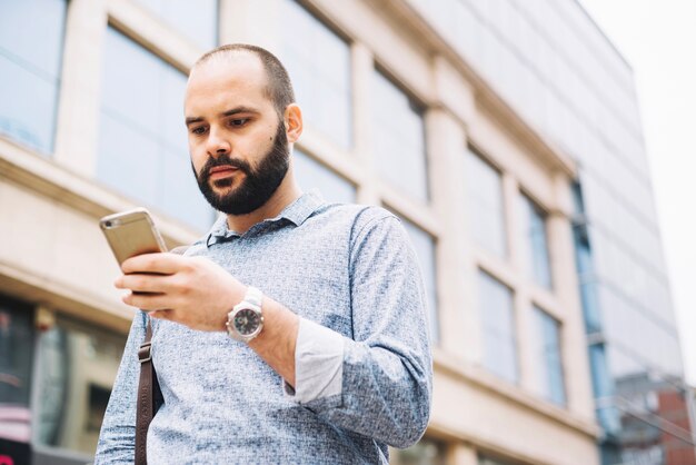 Poważny elegancki człowiek patrząc na telefon