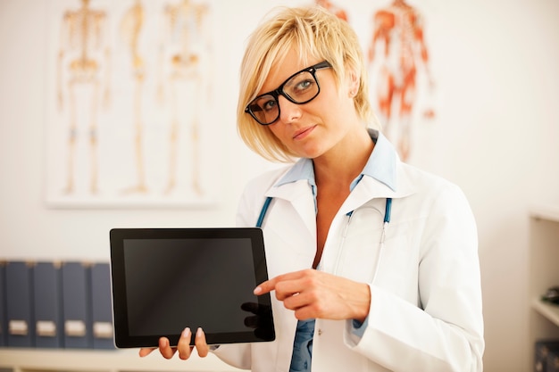 Bezpłatne zdjęcie poważny lekarz, wskazując na cyfrowy tablet