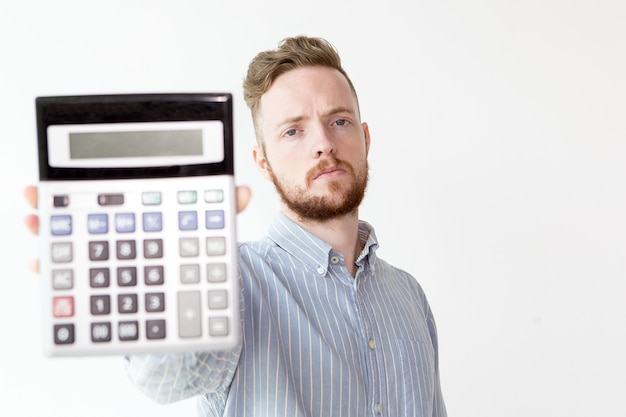 Bezpłatne zdjęcie poważny manager rozciąga dłonią z kalkulatora