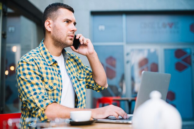 Poważny mężczyzna opowiada na telefonie przy lunchem