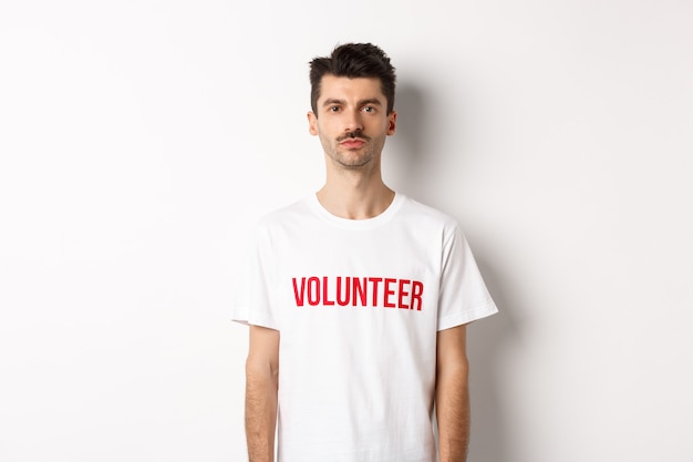 Poważny młody wolontariusz w białej koszulce patrzący w kamerę, gotowy do pomocy