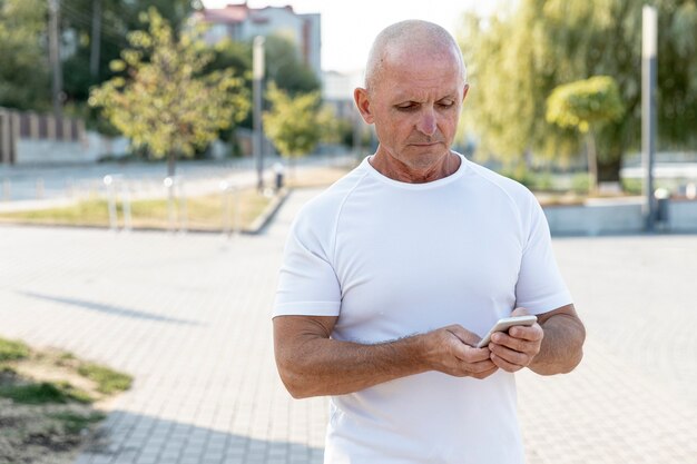 Poważny starszy mężczyzna cheking jego telefon