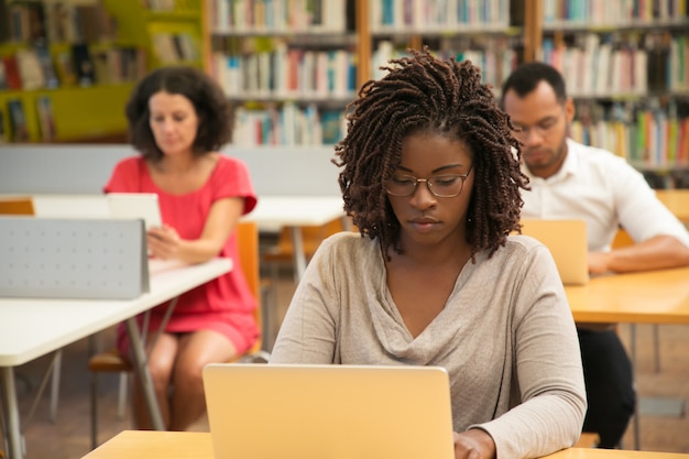 Poważny student African American studiuje w bibliotece
