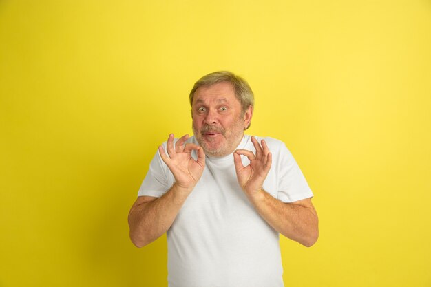 Powitanie, zapraszający gest. Portret kaukaski mężczyzna na białym tle na żółtym tle studio. Piękny model mężczyzna w białej koszuli pozowanie. Pojęcie ludzkich emocji, wyraz twarzy, sprzedaż, reklama. Copyspace.