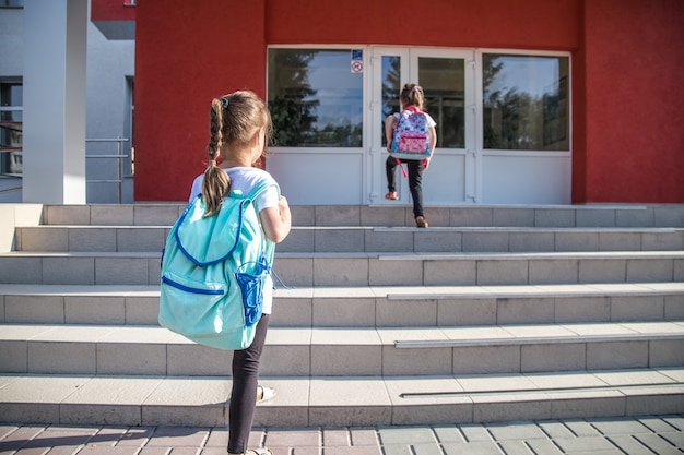 Bezpłatne zdjęcie powrót do koncepcji edukacji szkolnej z dziećmi dziewczynki, uczniów szkół podstawowych, niosąc plecaki do klasy