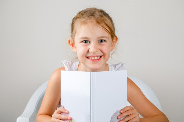Powrót do widoku z boku koncepcji szkoły. mała dziewczynka trzyma książkę.