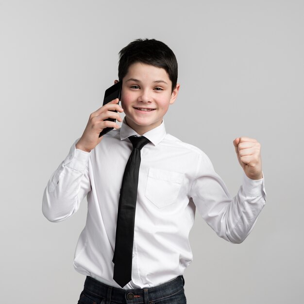Pozytywna młoda chłopiec opowiada na telefonie komórkowym