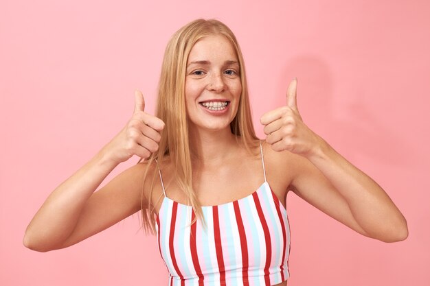 Pozytywna, optymistyczna nastolatka robiąca kciuki, zachęcająca do kliknięcia jak przycisk, podekscytowana dobrą wiadomością
