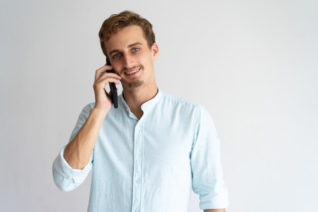 Pozytywny męski kierownik opowiada na telefonie komórkowym.