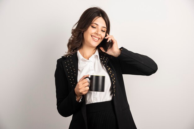 Pozytywny pracownik rozmawia przez telefon trzymając herbatę