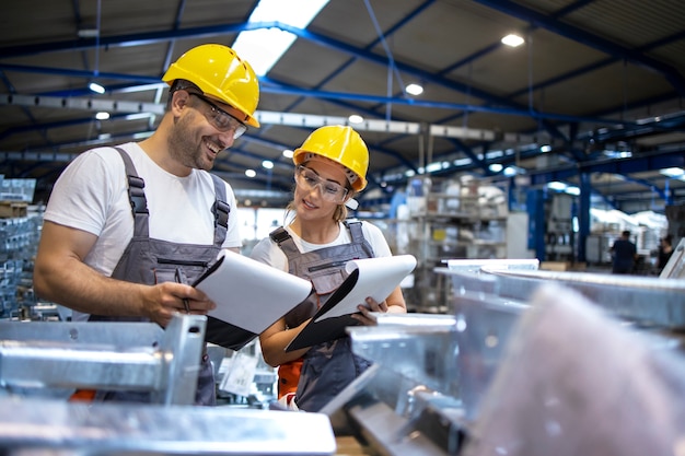 Pracownicy fabryki analizujący wyniki produkcji w dużej hali przemysłowej