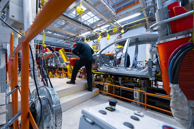 Pracownicy montują samochód nowoczesna zautomatyzowana linia montażowa samochodów najnowsze neutralne technologicznie technologie produkcji samochodów w zakładzie Montaż samochodów na przenośniku