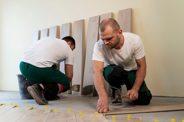 Pracownicy zajmujący się pełnym ujęciem układający podłogę w pomieszczeniu