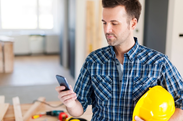 Bezpłatne zdjęcie pracownik budowlany z współczesnym telefonem komórkowym