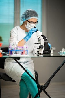 Pracownik medyczny prowadzący badania laboratoryjne z mikroskopem, probówkami, lekami, chemikaliami i analizami, badający wirusy i inne choroby ludzkie