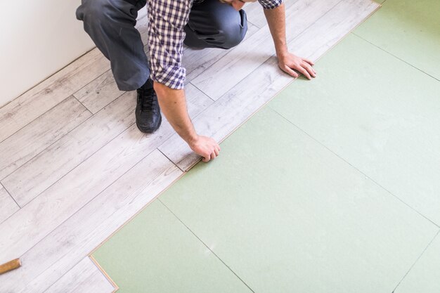 Pracownik obrabiający podłogę z jasnymi laminowanymi deskami podłogowymi