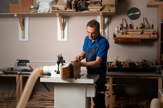 Bezpłatne zdjęcie pracownik obróbki drewna w swoim sklepie pracujący z narzędziami i sprzętem