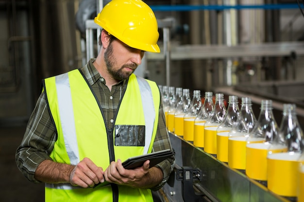 Pracownik płci męskiej za pomocą cyfrowego tabletu w fabryce soków