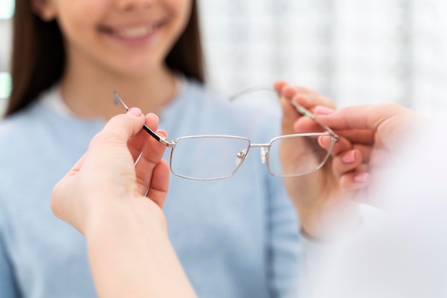 Pracownik pomaga dziewczynie przymierzyć okulary