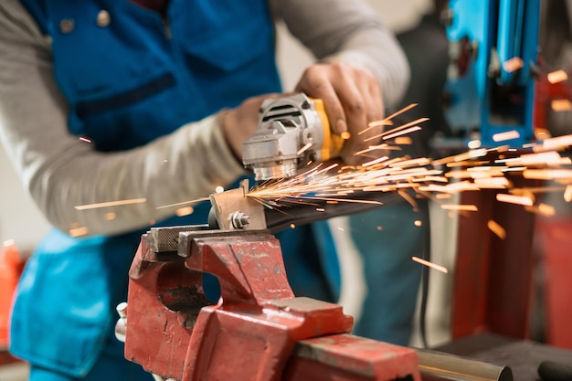 Pracownik pracujący z szlifierką okrągłą na metalu z iskrami