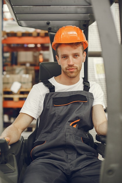 Pracownik przemysłowy w fabryce w pomieszczeniu. Młody technik z pomarańczowym ciężkim kapeluszem.