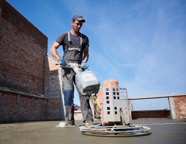 Bezpłatne zdjęcie pracownik przy użyciu zacieraczki na placu budowy