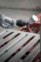 Bezpłatne zdjęcie pracownik rozpylający farbę proszkową z boku pistoletu