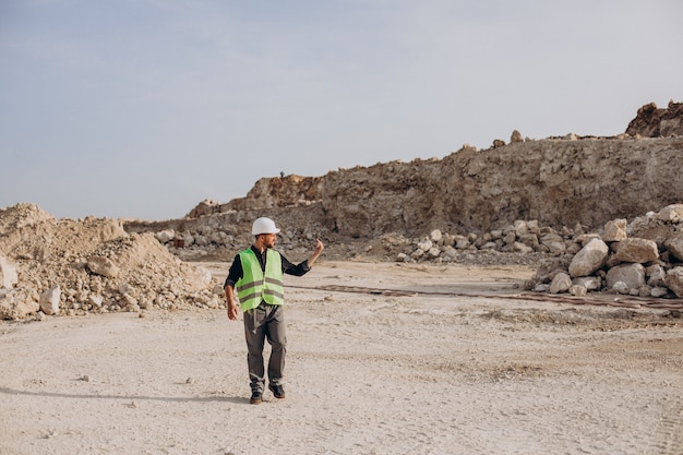 Pracownik w kasku stojący w kamieniołomie piasku
