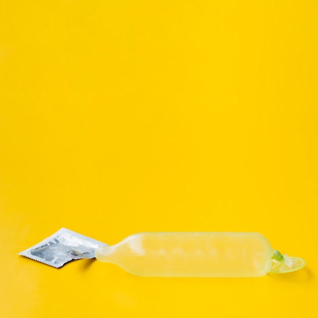 Prezerwatywa wypełniona wodą i opakowanie na żółtym tle