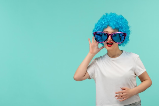 Bezpłatne zdjęcie prima aprilis klaun dziewczyna słuchająca ucha dotykająca brzucha duże niebieskie okulary zabawny kostium niebieskie włosy