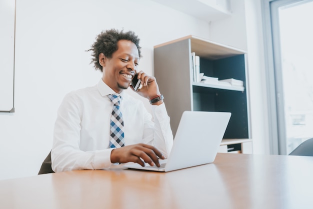 Profesjonalny biznesmen rozmawia przez telefon i za pomocą laptopa podczas pracy w biurze. pomysł na biznes
