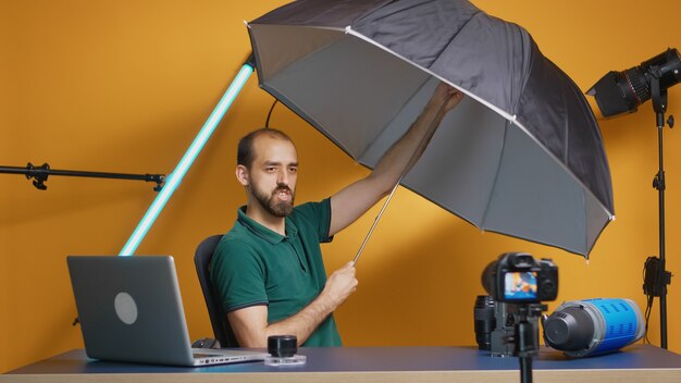 Profesjonalny fotograf nagrywający recenzję parasola w studio. Profesjonalna technologia studyjnego sprzętu wideo i fotograficznego do pracy, gwiazda mediów społecznościowych studia fotograficznego i influencer