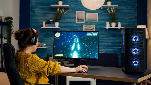 Profesjonalny gracz grający w strzelankę FPS online na potężnym komputerze osobistym z kolorowymi neonowymi światłami. Cyber występujący na komputerze w stylowym pokoju podczas turnieju gier
