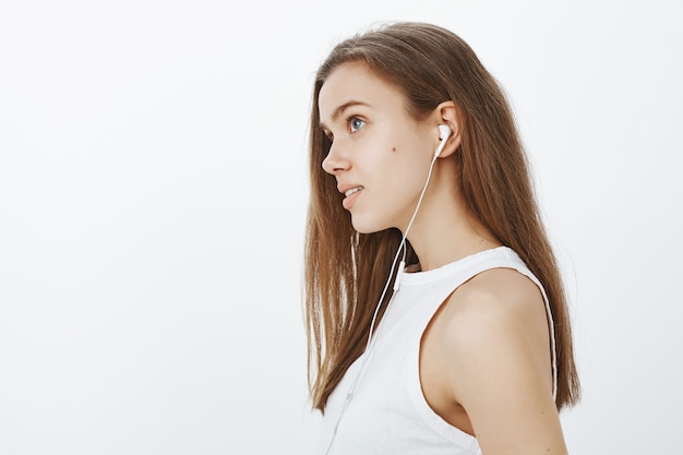 Profil marzycielskiej atrakcyjnej dziewczyny słuchającej podcastu lub muzyki w słuchawkach
