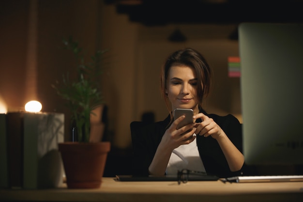 Projektant całkiem młoda kobieta siedzi w pomieszczeniu rozmawiać przez telefon