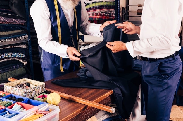Projektant mody pokazujący tkaninę swojemu klientowi w sklepie