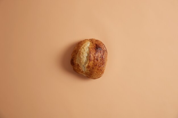 Przaśny chleb francuski w okrągłym kształcie przygotowany z organicznej naturalnej mąki, na białym tle na beżowym tle. Eko koncepcja życia i żywności ekologicznej. Domowy, świeżo upieczony bochenek chleba. Koncepcja piekarni