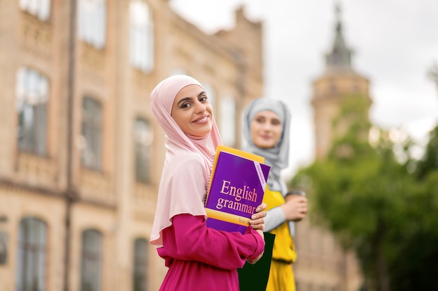Przed lekcjami angielskiego. muzułmański uczeń czuje się podekscytowany przed angielskim podczas spaceru z przyjacielem