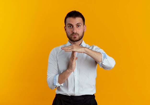 Przekonany, przystojny mężczyzna gestykuluje ręką znak na białym tle na pomarańczowej ścianie