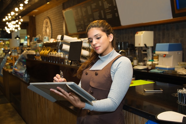 Przekonany właściciel kawiarni pisze w księdze rejestracyjnej