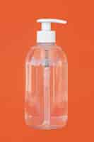 Bezpłatne zdjęcie przezroczysta butelka mydła w płynie na pomarańczowym tle