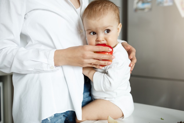 Przycięte zdjęcie matki, podając dziecko kawałek jabłka