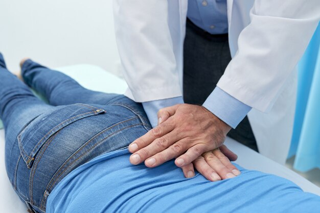 Przycięty osteopata dopasowujący plecy pacjenta podczas masażu