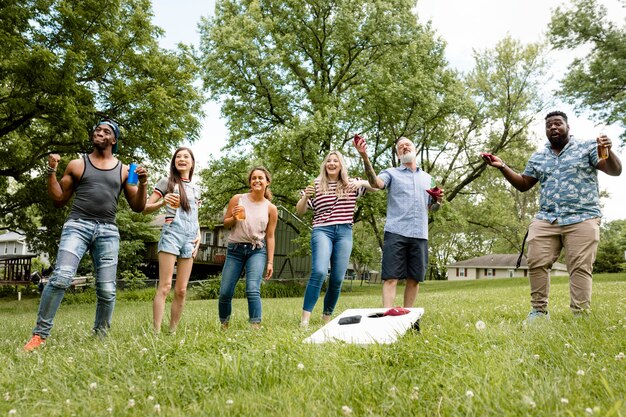 Przyjaciele bawią się w cornhole na letniej imprezie w parku