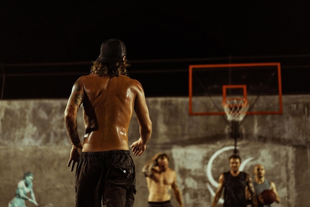 Bezpłatne zdjęcie przyjaciele grają w koszykówkę. młodzi mężczyźni grają w koszykówkę na ulicy.