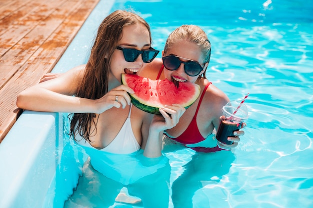 Przyjaciele na basenie jedzą arbuza