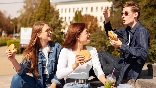 Przyjaciele na świeżym powietrzu jedzą hamburgery