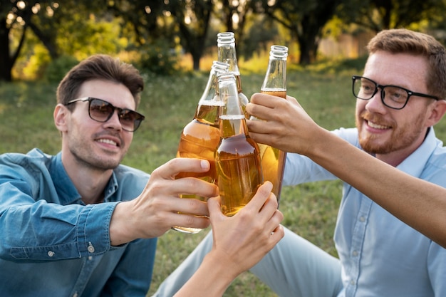 Przyjaciele na zewnątrz w parku piją razem piwo