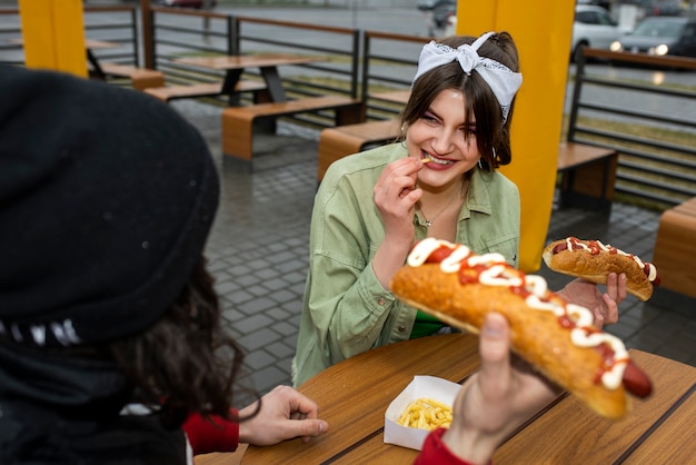 Przyjaciele pod dużym kątem jedzący hot dogi